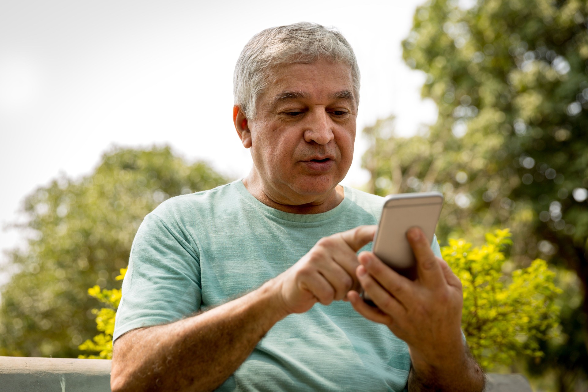 Senior hombre escribir mensaje en el Parque
